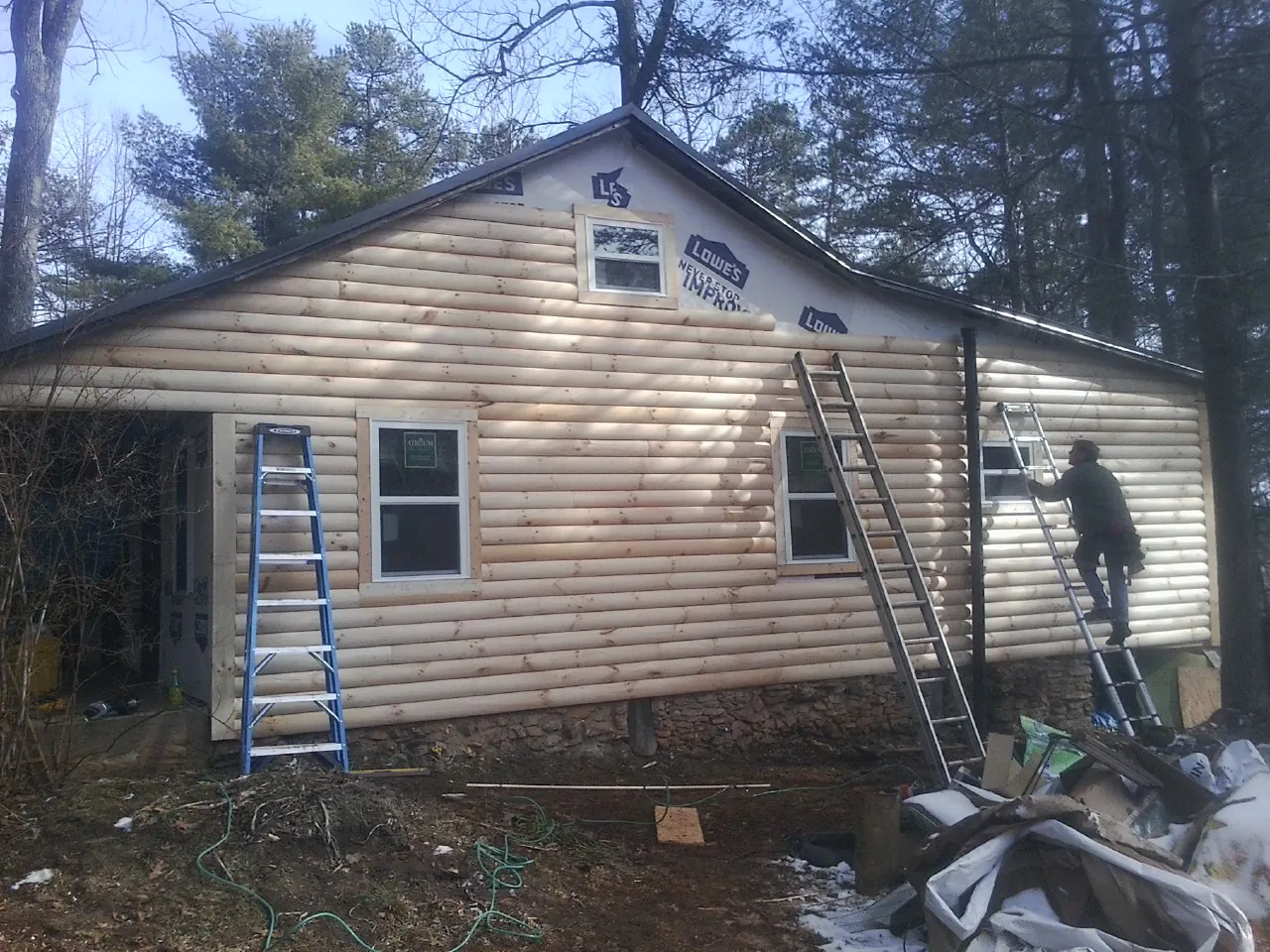 Ladders set against fresh log siding during an exterior remodel in Hicksville