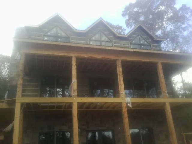 Dormers and porch framing on a large log home under construction — Roof Coating work by our crew in Hicksville